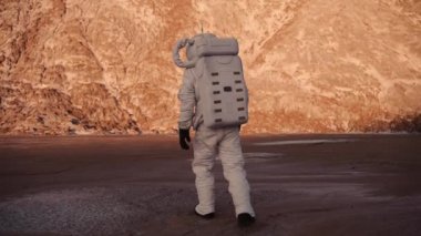 Astronot tepeye doğru yürüyor. Astronot bilinmeyen bir gezegende yürüyor.