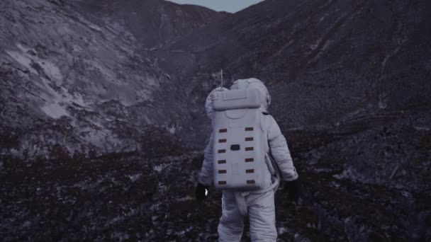 Ein Astronaut in der Abenddämmerung mit einer Laterne in der Hand erklimmt den Hügel — Stockvideo