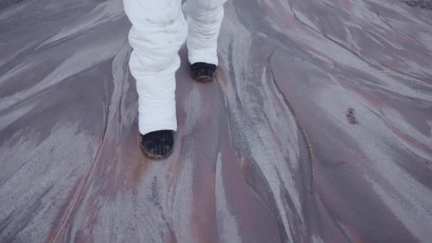 Astronaut walks slowly and carefully on the solid surface of an unknown planet — Stock Video