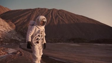 Astronot akarsu boyunca dikkatlice yürür ve elini kaldırır.. 