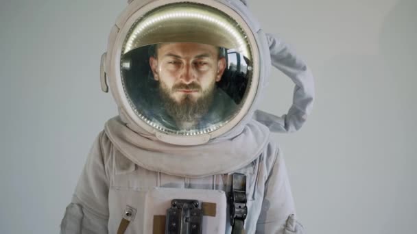 Een astronaut met een serieus gezicht staat tegen een lichte achtergrond. studio — Stockvideo