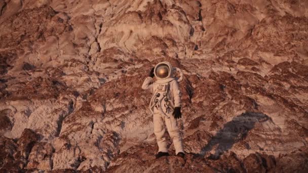 Astronauta de pé sobre uma rocha abre a aba de seu capacete. o sol está brilhando — Vídeo de Stock