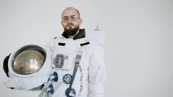 Astronauta w okularach i z kaskiem w ręku na jasnym tle. studio — Wideo stockowe