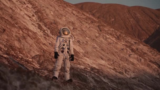 An astronaut stands on a rock and looks into the distance.camera moves at him — Stock Video