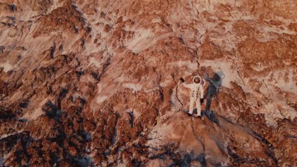 Astronaut standing on a rock waving hand. aerial photography — Stock Video