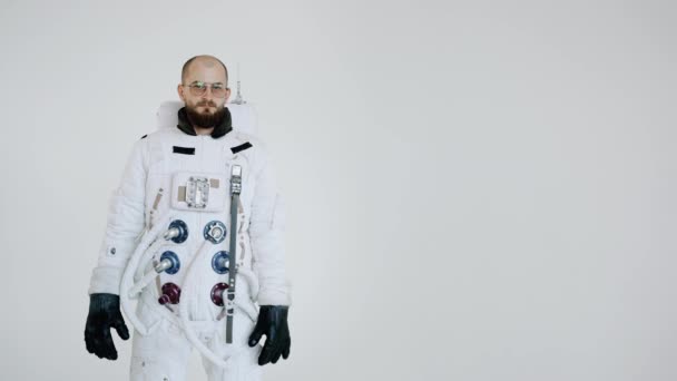Astronauta si erge su uno sfondo chiaro con una grave espressione sul viso — Video Stock