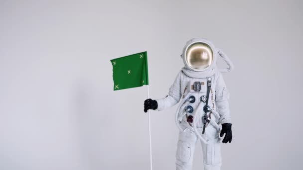 Astronauta ergue-se com uma bandeira sobre um fundo claro. estúdio — Vídeo de Stock