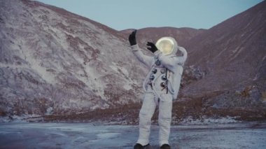 Astronot elinde telefonla tepelerde görüntülü konuşma yapıyor.