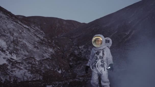 Um astronauta ao entardecer com uma lanterna desce a colina através de uma nuvem de vapor — Vídeo de Stock
