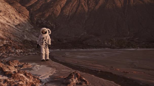 El astronauta camina cautelosamente a lo largo del arroyo, levanta la mano. — Vídeos de Stock