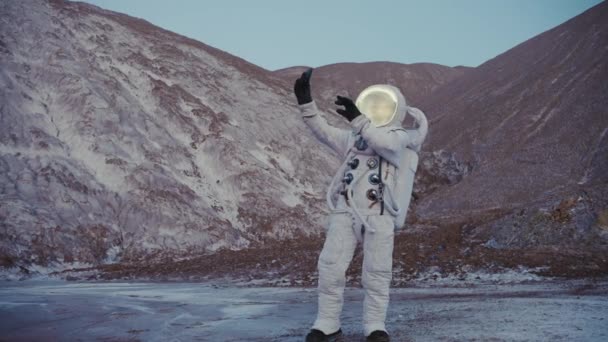 Astronauta com telefone na mão conversando em vídeo chat nas colinas — Vídeo de Stock