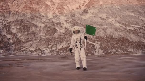 Astronauta sta camminando su un pianeta sconosciuto. Sole splende. tramonta la bandiera — Video Stock