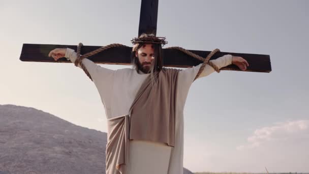 Jesús crucificado en la cruz, el viento sopla, el sol brilla. De cerca. — Vídeos de Stock