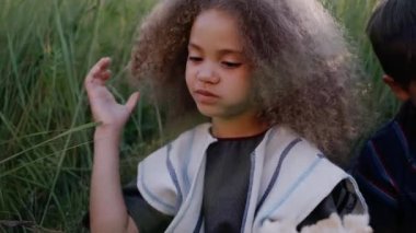 Bir kız ve bir oğlan, kulak tarlasında otururken ekmek çiğniyorlar..