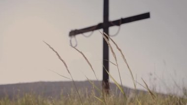 Çarmıha gerilme haçı tepede duruyor. Kulaklar ön planda sallanıyor