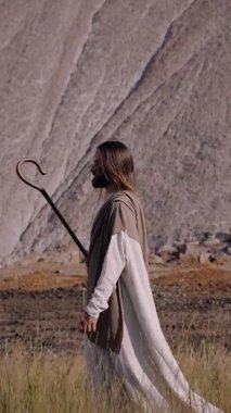 Personeli olan İsa, yılın arka planında çimenlerde yürüyor.