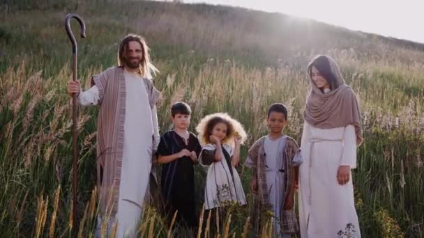 Jesús con cosas, niños y María entre las orejas en la colina. Sol brillando — Vídeo de stock