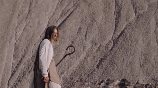 Jezus met een staf wandelt tegen de achtergrond van het jaar. Kijkend naar camera. — Stockvideo