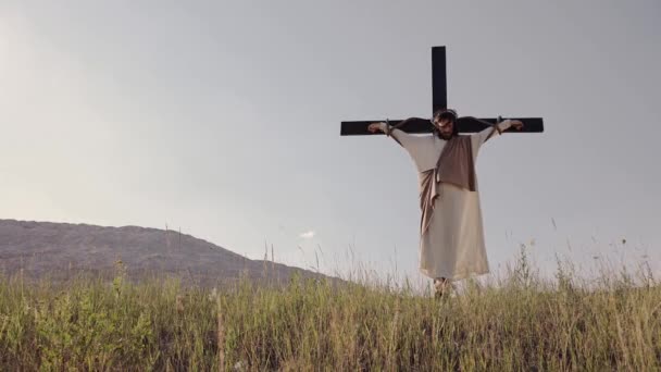 Jesús cuelga en la cruz, el viento sopla, el sol brilla. Crucifixión. — Vídeo de stock