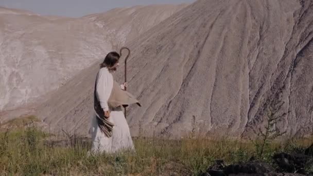 Ο Ιησούς με το ραβδί περπατά στο γρασίδι στο φόντο του έτους. — Αρχείο Βίντεο