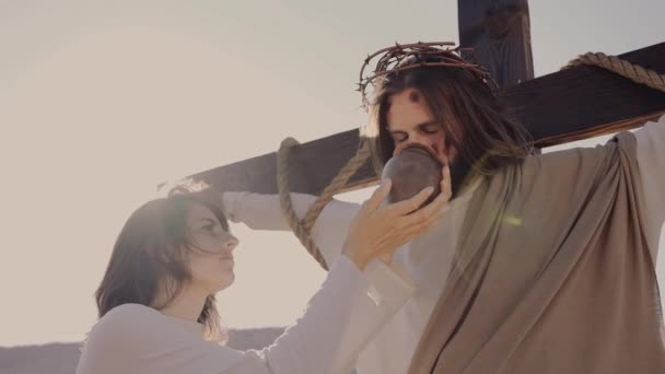 María da agua a Cristo crucificado en la cruz. Corona de espinas. Sol brillar. — Vídeos de Stock