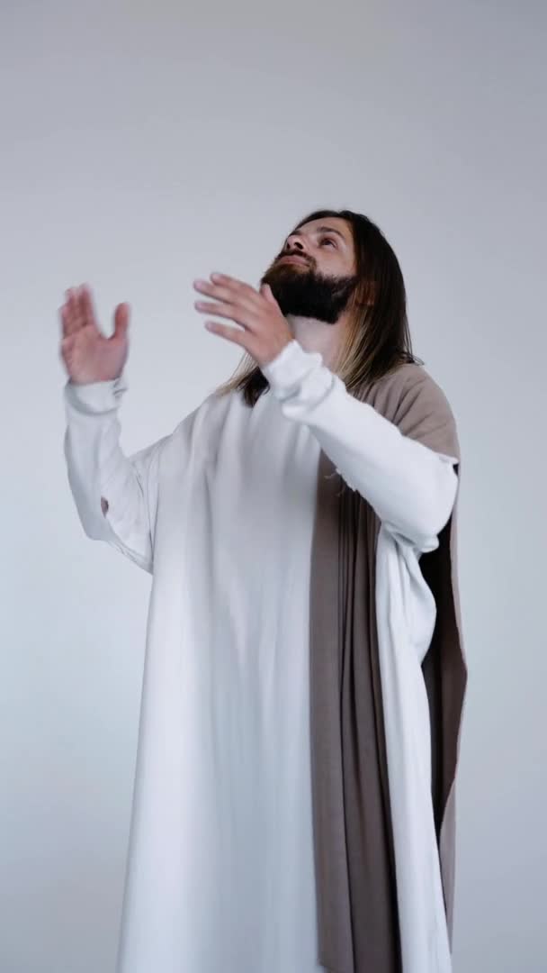 Jezus bidt met zijn handen bij elkaar op een witte achtergrond. Verticaal. Studio — Stockvideo