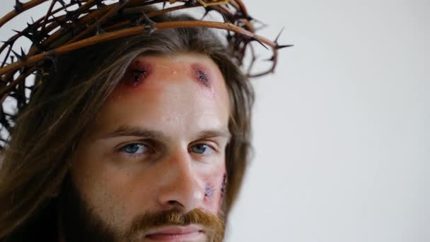 Jesus in a crown of thorns with wounds on face looks into the camera. Close up — Stock Video