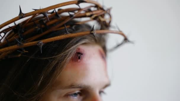 Ο Ιησούς σε ένα στεφάνι από αγκάθια με πληγές στο πρόσωπο σε λευκό φόντο. Κλείσε. — Αρχείο Βίντεο