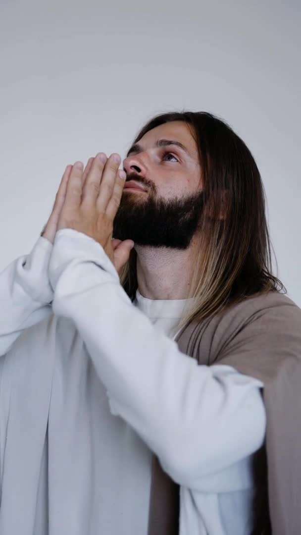 Jesús ora con las manos juntas sobre un fondo blanco. Vertical. Estudio — Vídeos de Stock