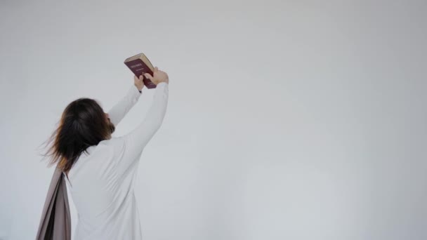 Jesus raised the Bible in his hands above his head on a white background.Studio. — Stock Video