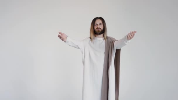 Gesù in vestaglia stende le mani ai lati chiedendo la preghiera. Studio. — Video Stock