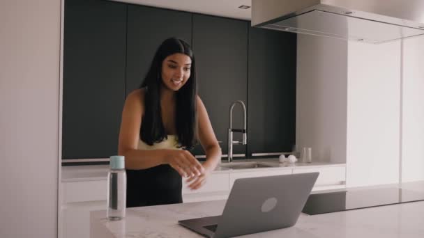 Jong donker gevild brunette in de keuken met een laptop, video chatten — Stockvideo