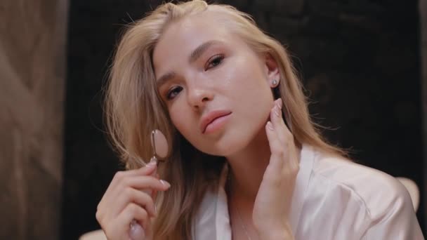 Fiatal szőke nő fehér köntösben a fürdőszobában egy görkori masszírozóval — Stock videók