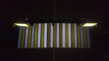 Gece boyunca boş yaya geçidine tepeden bakan drone görüntüsü. Bazen arabalar geçer. Trafik ışıkları yanıp sönüyor ve yol işaretleri yanıyor..