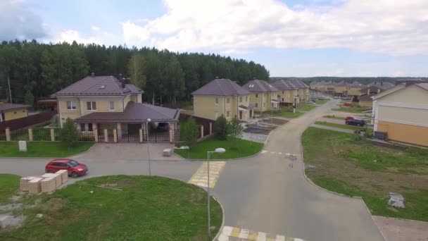 夏の通りの上空のドローン映像 近代的な高級住宅 住宅街を空飛ぶ アスファルトの道路や歩道 他の村の近く 曇った夏の日 — ストック動画