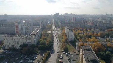 Sonbahar büyük şehrinin havadan görünüşü. Çok katlı binalarda ve otoparkta. Arabalar caddelerden geçer. Ağaçlardaki yapraklar sararmaya başladı. Şehrin üzerinde sis var.