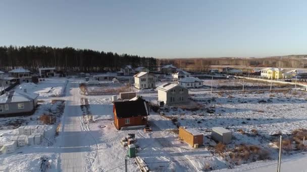 冬のコテージ村の建設中の家の空中ビュー 村の周りに森林や畑があります 建設のための無料の地面があります — ストック動画