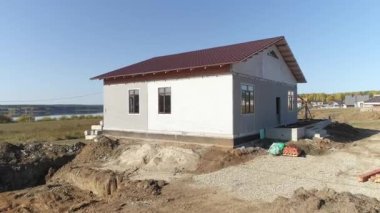 Tamamlanmamış modern enerji verimliliğine sahip köpük bloklardan yapılmış çelik kiremit kaplamalı panellerin insansız hava aracı görüntüsü. Köydeki ev. Güneşli bir gün