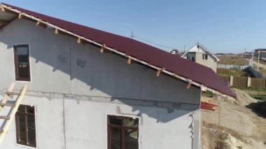 Tamamlanmamış modern enerji verimliliği olan köpük bloklu evlerin metal kaplamalı çatılarının havadan görünüşü. Köydeki ev. Güneşli bir gün