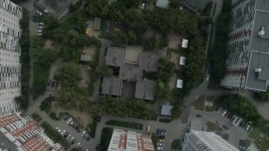 Konut alanındaki boş anaokulu binası, ağaçlar arasında oyun parkları ve asfaltta çocukların çizimleri. Kamera döndürür