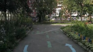 Anaokulu binası yakınlarındaki ağaçların arasındaki asfaltta çocukların çizimlerini gösteren drone görüntüsü