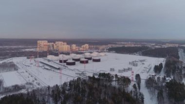 Konut alanı yakınlarındaki petrol deposunun havadan görüntüsü. Petrol deposu ve çok katlı binaların manzarası. Kış akşamı.