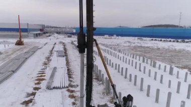 Yığın delici makinenin kış inşaatındaki bir kısmının hava aracı görüntüsü. Birçok güçlendirilmiş beton yığını zaten makinenin yanındaki yere sürüldü. Bölgede pekçok beton yığını var.
