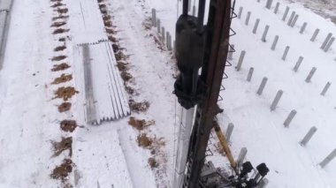Kış şantiyesinde çalışan bir kazık delici makinenin hava aracı görüntüsü. Yüksek çarpışma ağırlık sürücüleri yerin derinliklerine yığılıyor. Bölgede pekçok güçlendirilmiş beton yığını var. Kış bulutlu gün