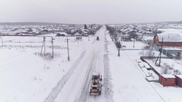 从空中俯瞰全村白雪公主等级清空白雪覆盖的乡间小路 另一辆拖拉机向他驶来 寒冷的冬季气候条件 — 图库视频影像