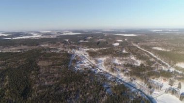 Sonsuz ormanlar arasında yer alan kış kır köyünün insansız hava aracı görüntüsü. Karla kaplı topraklar. Soğuk kış mevsiminde, güneşli bir günde çekilmiş. Bu muhteşem bir manzara manzarası..