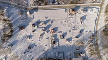 Sonsuz ormanlar arasında yer alan kış kulübelerinin tepeden aşağıya insansız hava aracı görüntüsü. Karla kaplı topraklar. Çocuklar için bir buz kaydırağı var. Bazı arsalar satılık ve inşaat için bedava. Soğuk kış mevsiminde vuruldu, güneşli bir günde..