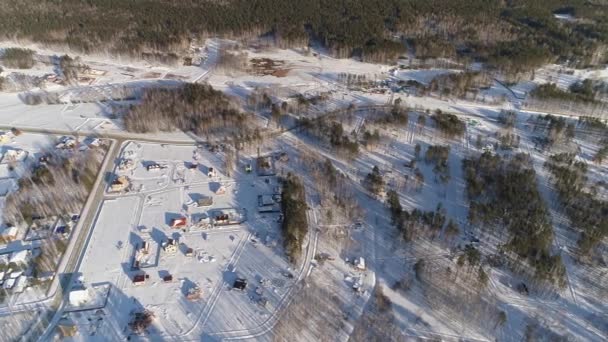 冬季村舍的空中无人俯瞰与冰上滑行的儿童座落在无尽的森林中 白雪覆盖的土地 有些地块是免费出售和建造的 在寒冷的冬季 阳光灿烂的日子拍摄 — 图库视频影像