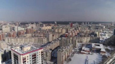 Tipik Sovyet panelleri ve büyük kış şehrindeki yeni modern yüksek binaların havadan görünüşü. Şehir ormanının yakınında. Arabalar caddelerden geçiyor. Şehirde kar yağışı var. Güneşli bir gün.