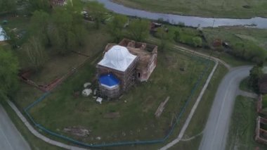 Eski köyün havadan görünüşü. Kilise nehrin yüksek kıyısında restore ediliyor. Tek katlı ahşap evleri olan bir köy. Evlerin yakınında sebze bahçeleri var. Yaz bulutlu günü